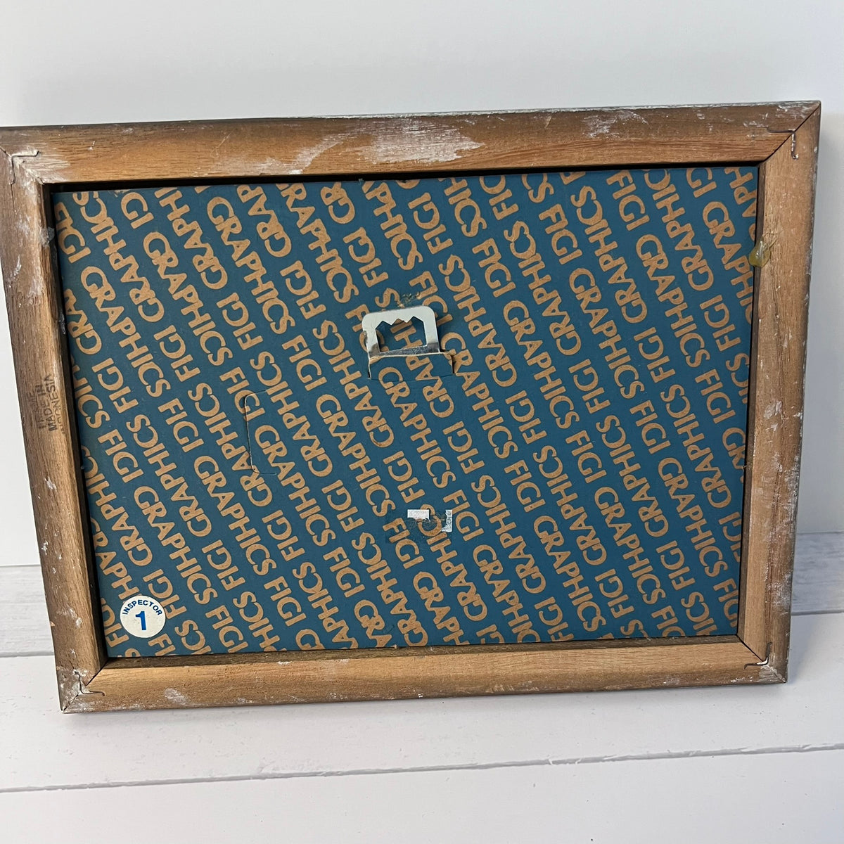 A rustic wooden picture frame with a distressed brown finish, holding a blue patterned insert printed with the word 'GRAPHIC' repeatedly, shown against a white background.