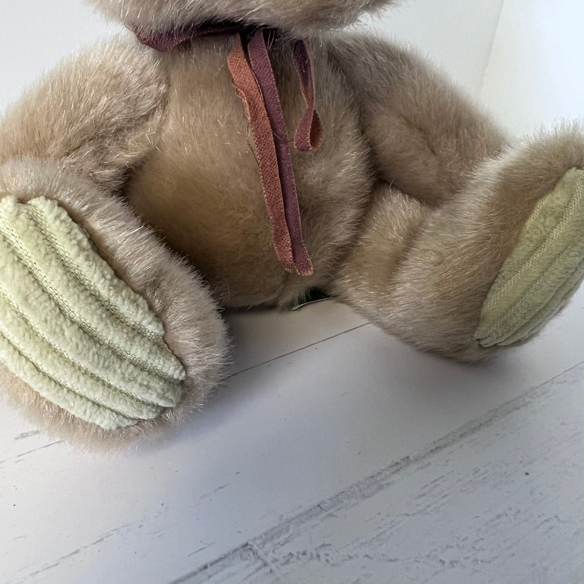 Close-up of a plush toy with yellow and brown elements on a white surface