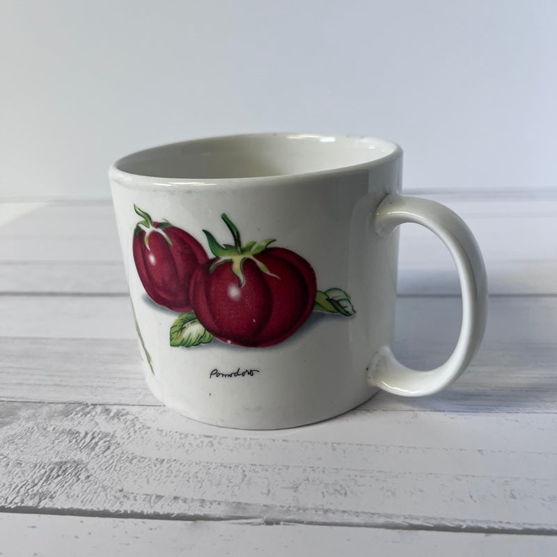 White mug with red fruit design on a white wooden surface