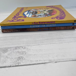Three books by Darby Conley stacked on a light wooden surface