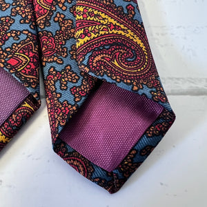 Colorful paisley tie with a matching pocket square on a white surface