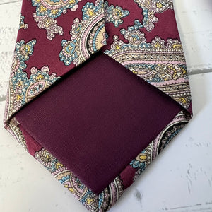 Burgundy paisley tie and pocket square on a white surface