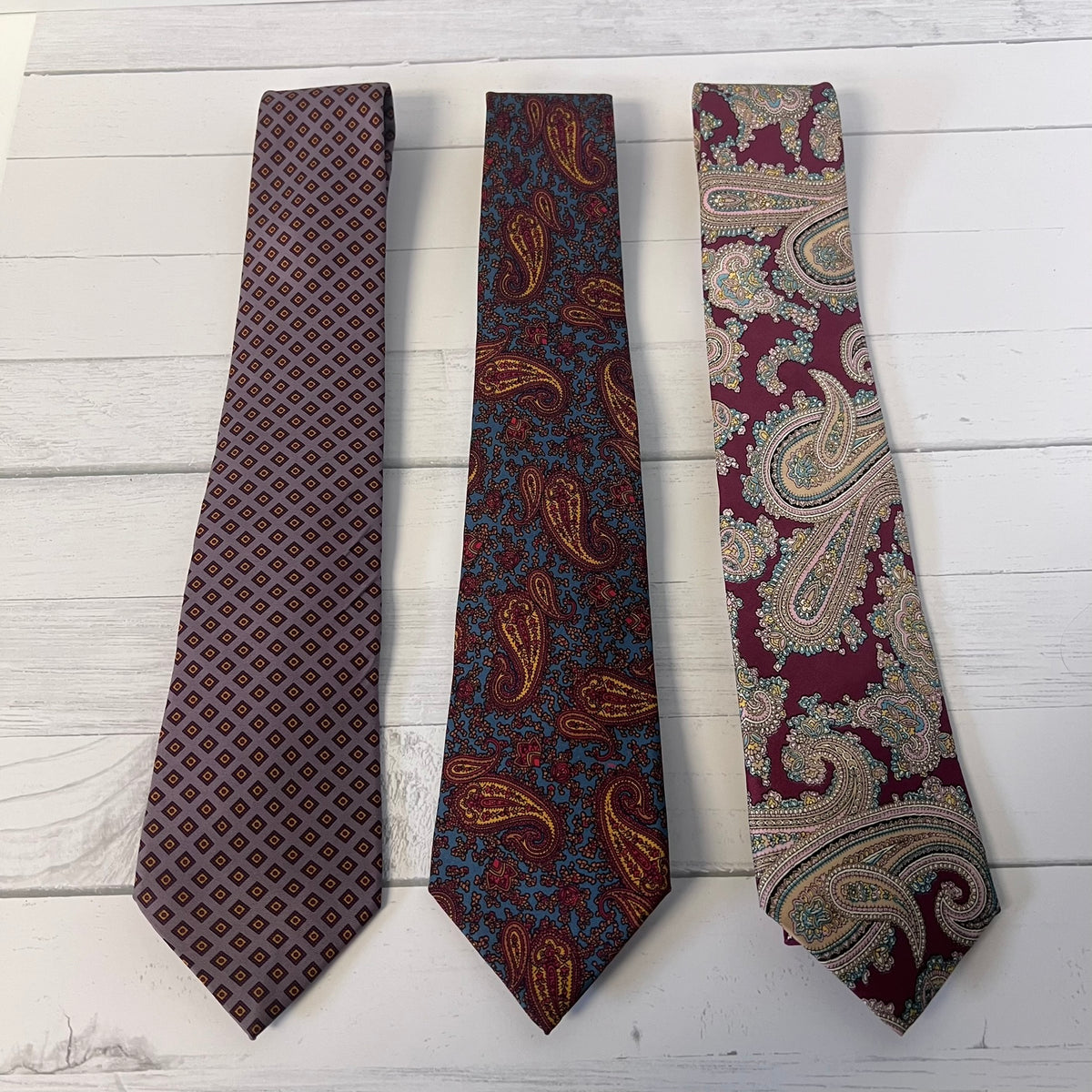 Three patterned ties on a light wooden surface