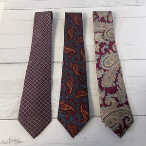 Three patterned ties on a light wooden surface