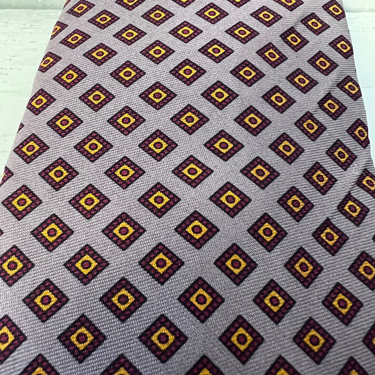 Navy and yellow patterned tie on a gray background