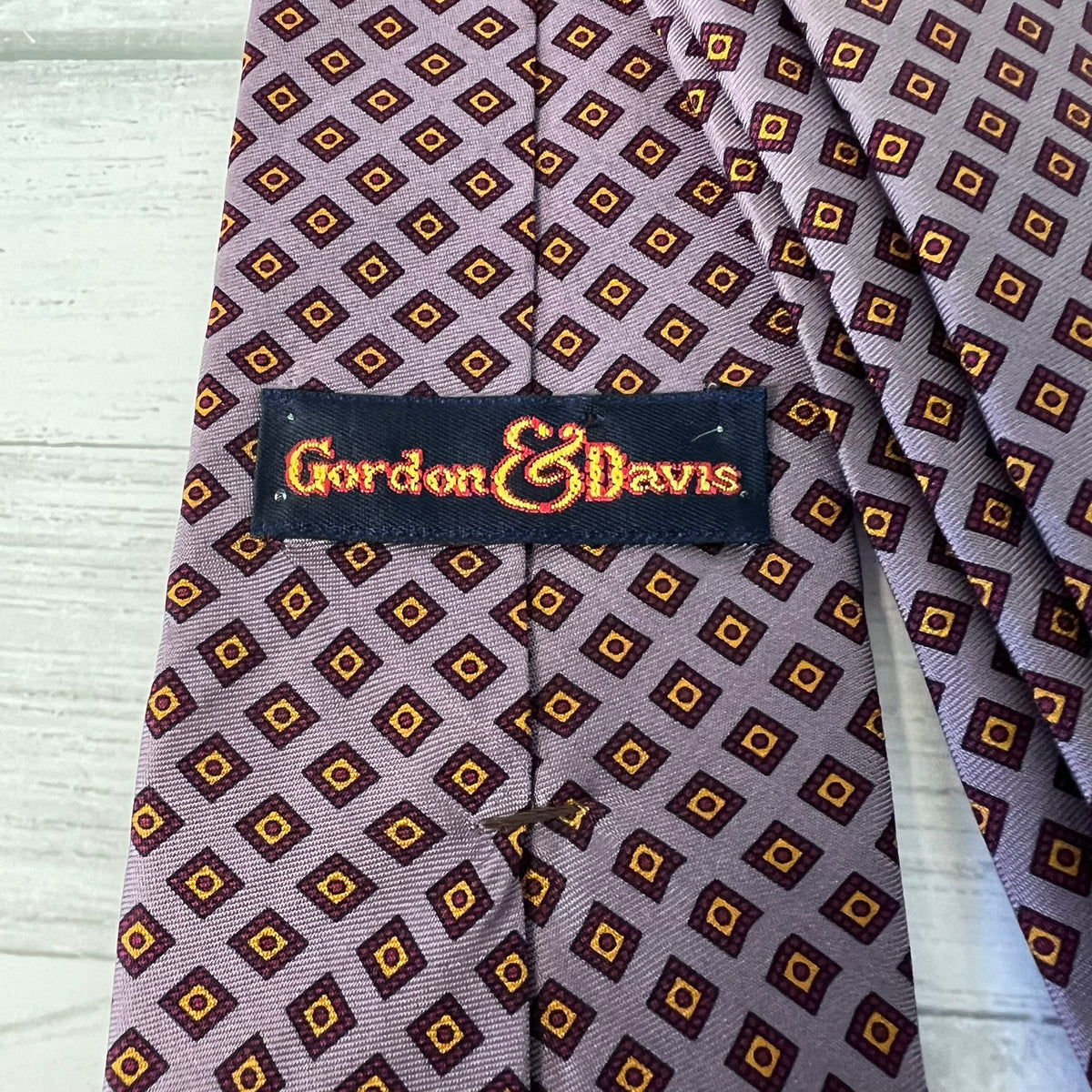 Patterned tie with 'Gordon & Davis' label on a wooden surface