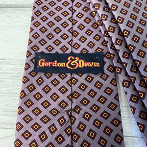 Patterned tie with 'Gordon & Davis' label on a wooden surface