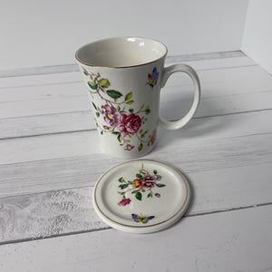 Mug and matching coaster with floral design on a white wooden surface