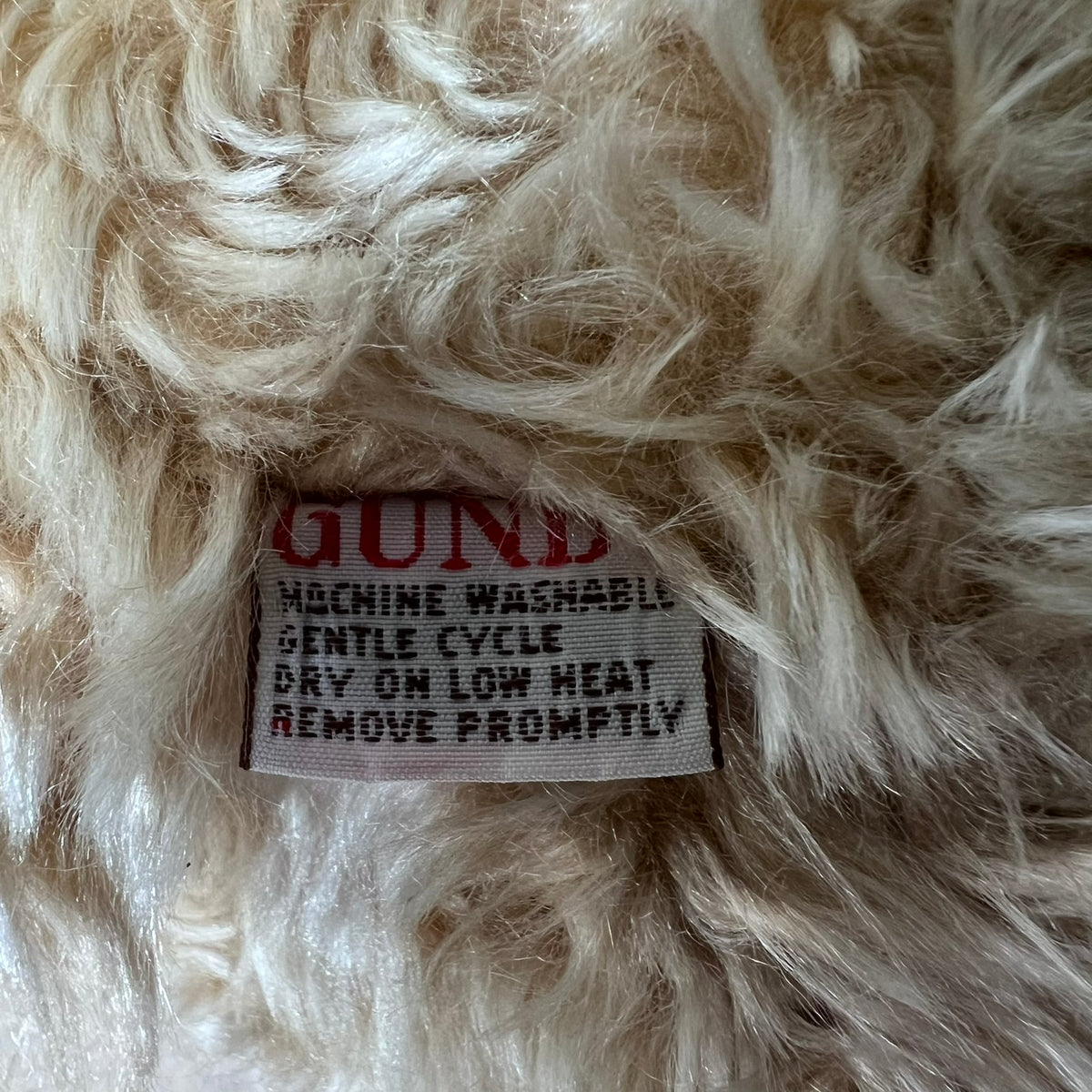 Close-up of a label on fluffy white fabric with text.