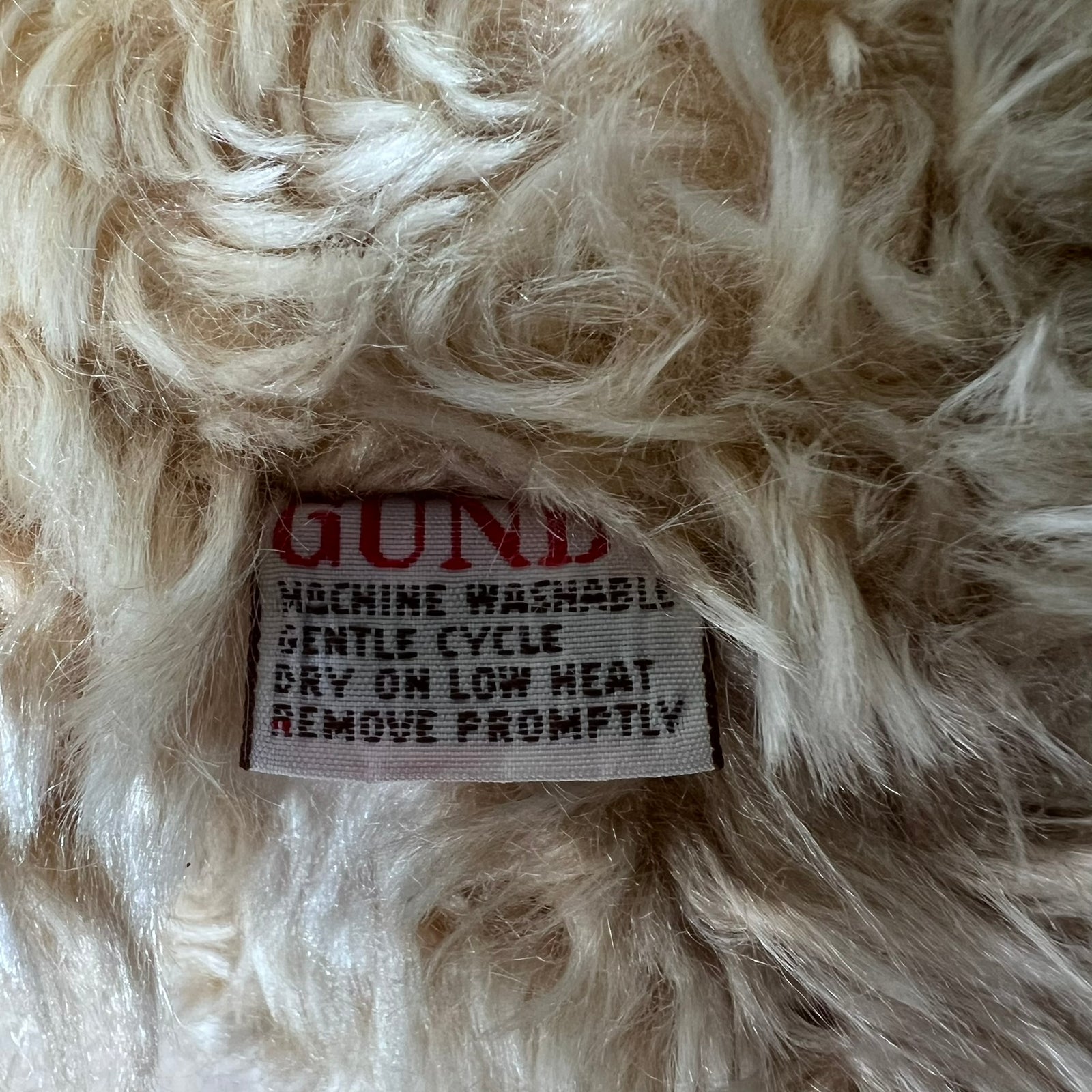 Close-up of a label on fluffy white fabric with text.