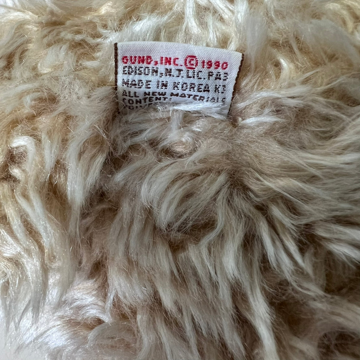 Close-up of a fluffy beige fabric with a visible label on a textured background