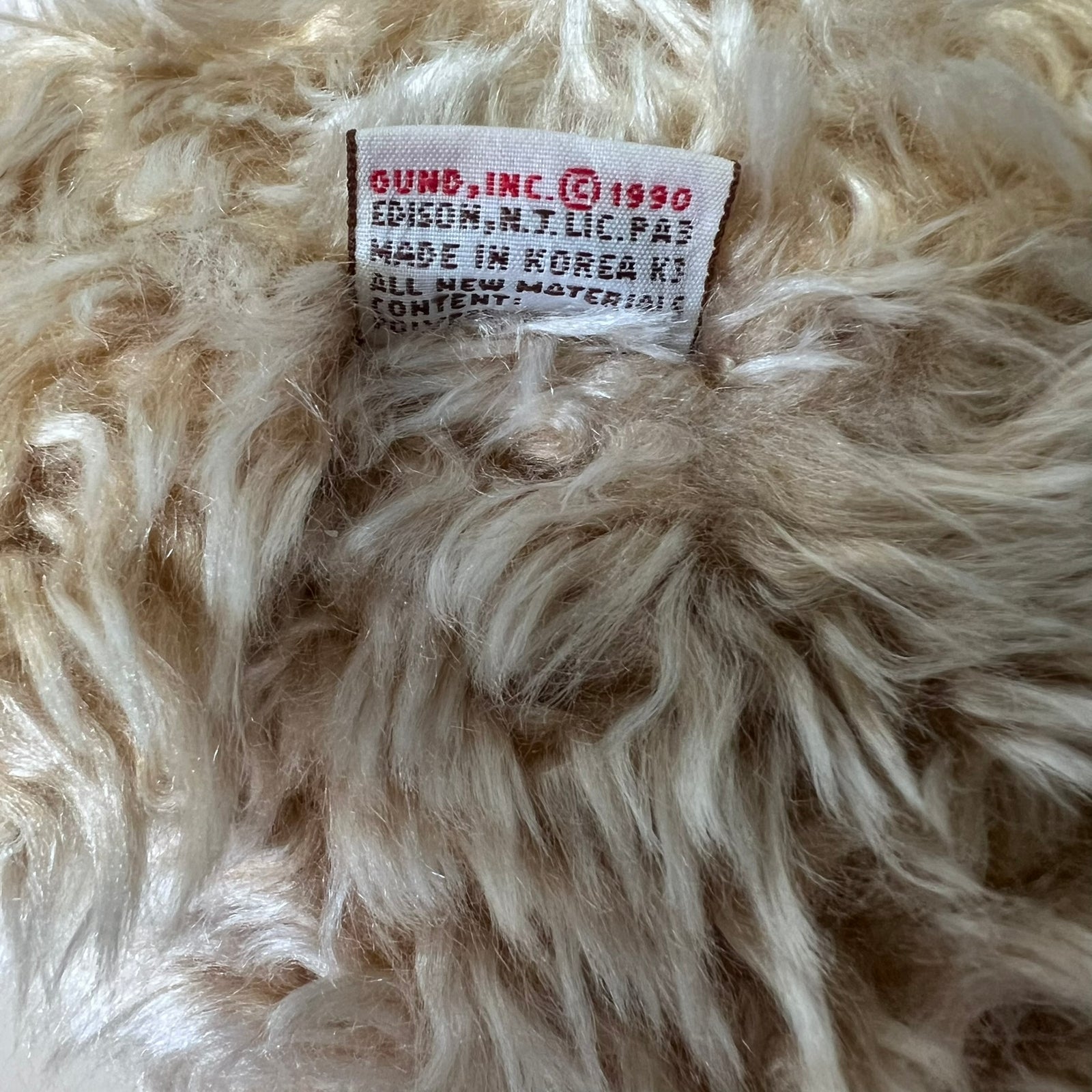 Close-up of a fluffy beige fabric with a visible label on a textured background