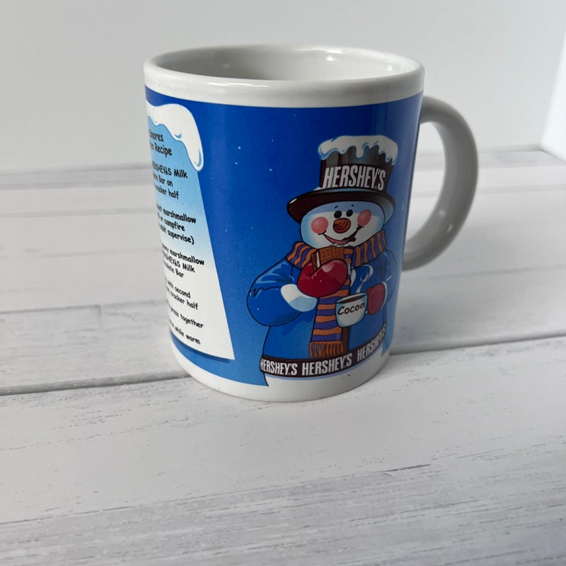 Blue mug with Hershey's snowman design on a white wooden surface