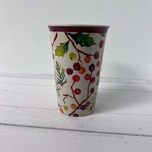 Decorative cup with holly design on a white wooden surface
