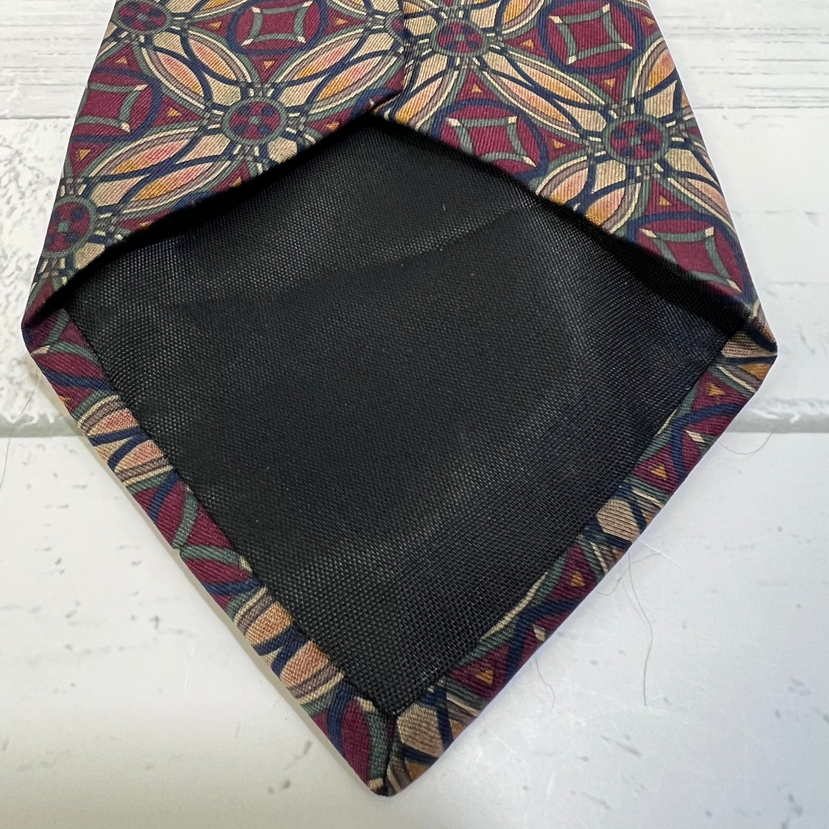 Black fabric square inside a patterned fabric frame on a white surface
