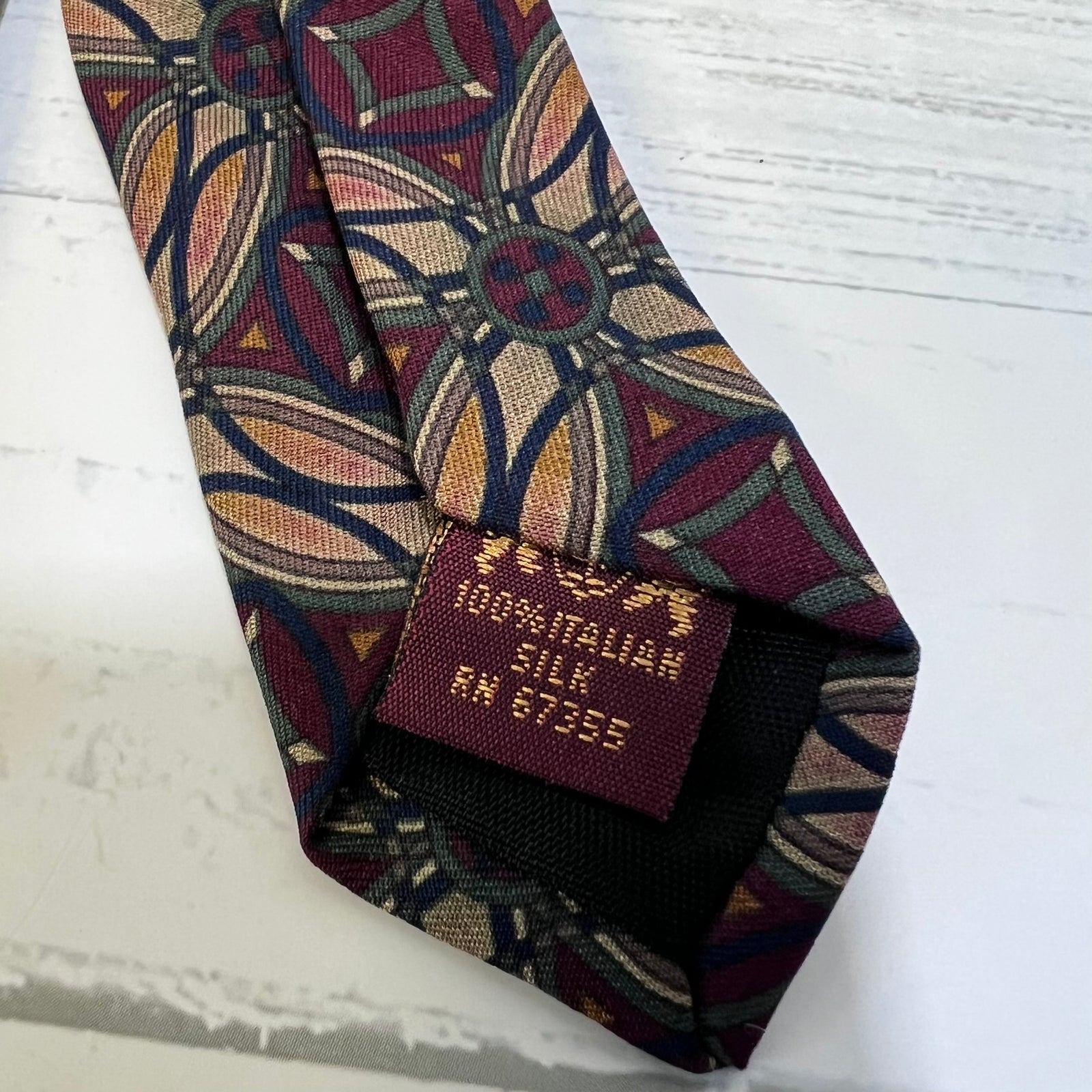 Patterned silk tie with a label on a light wooden surface