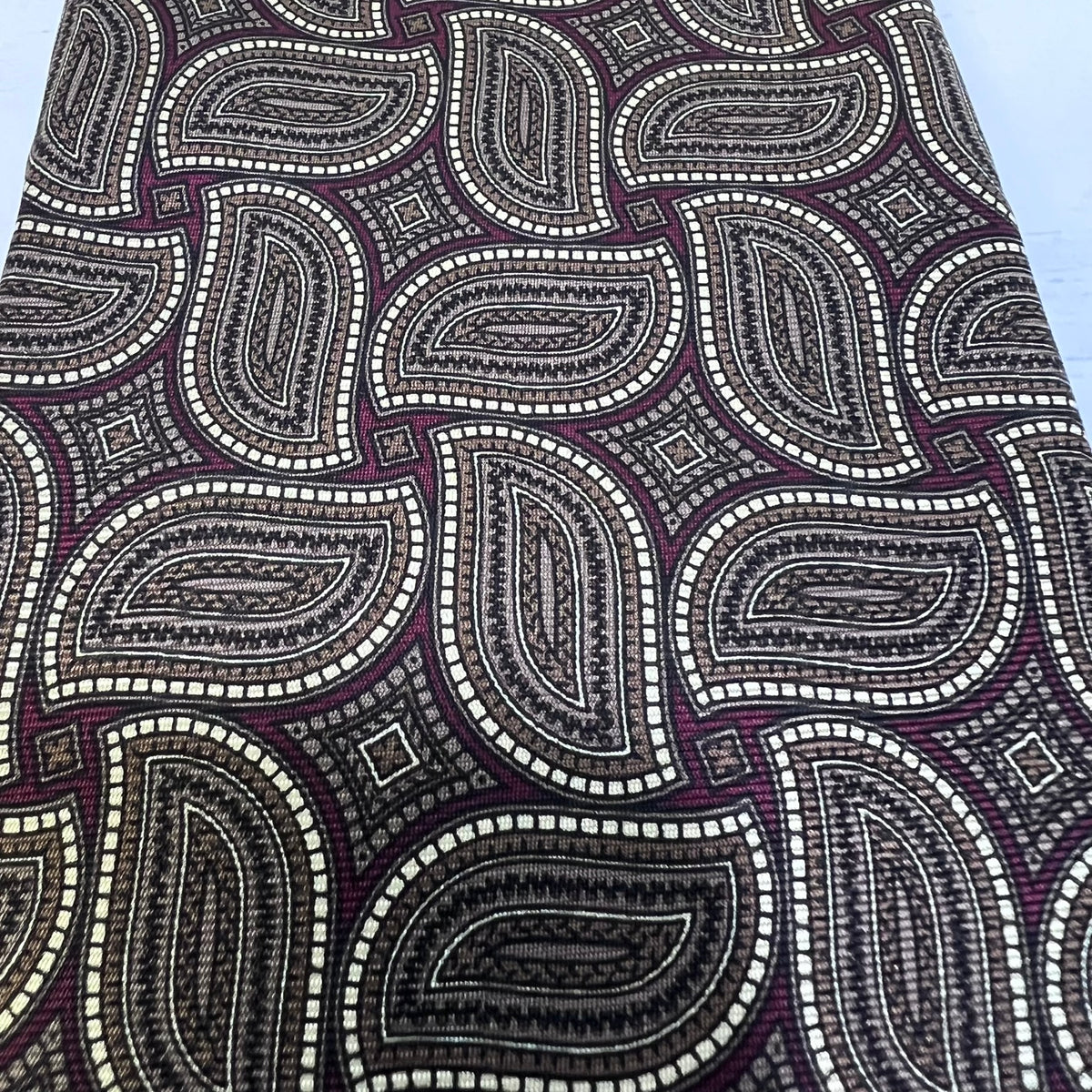Close-up of a patterned fabric with paisley design in black, white, and purple.