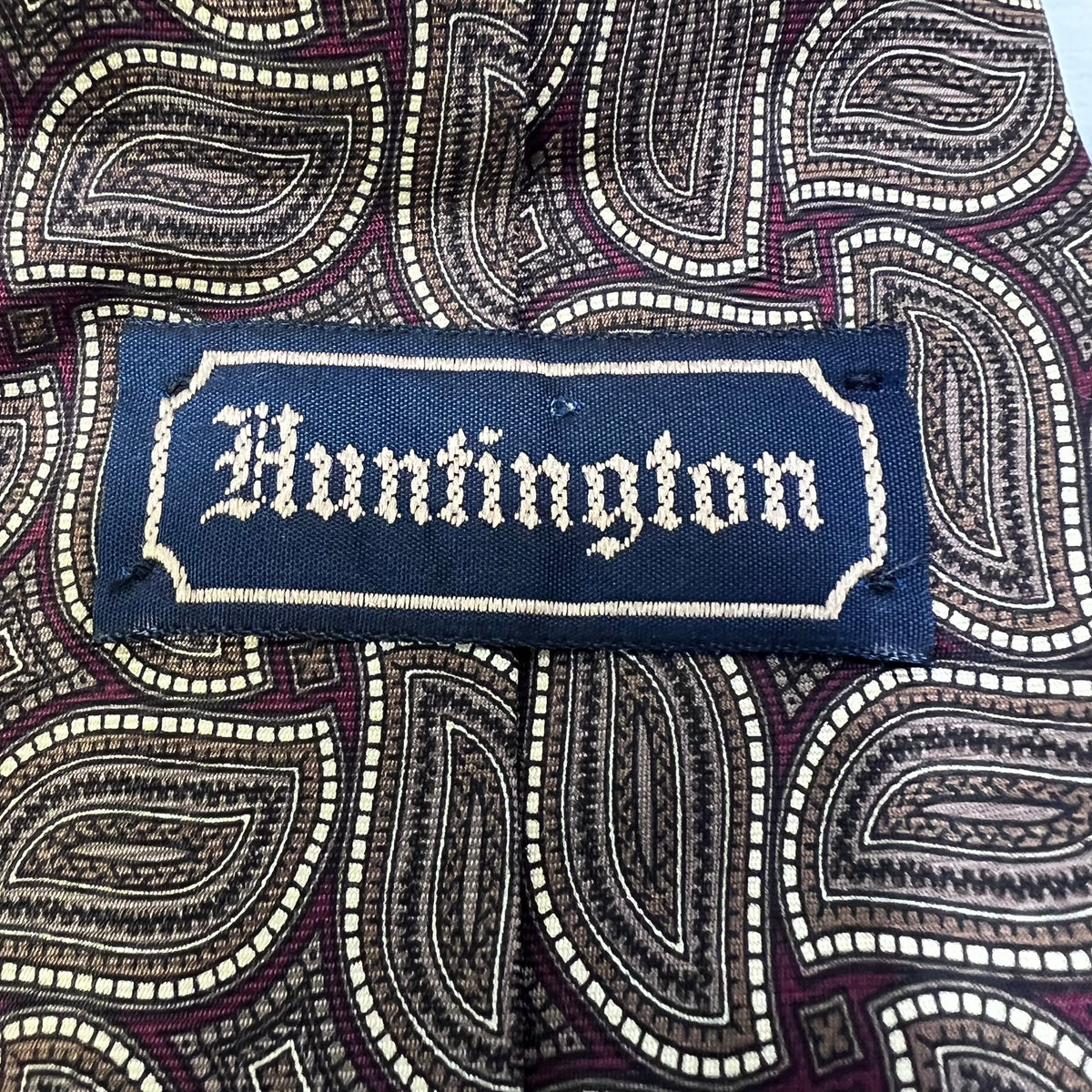 Fabric with a paisley pattern and a embroidered patch reading 'Huntington'.