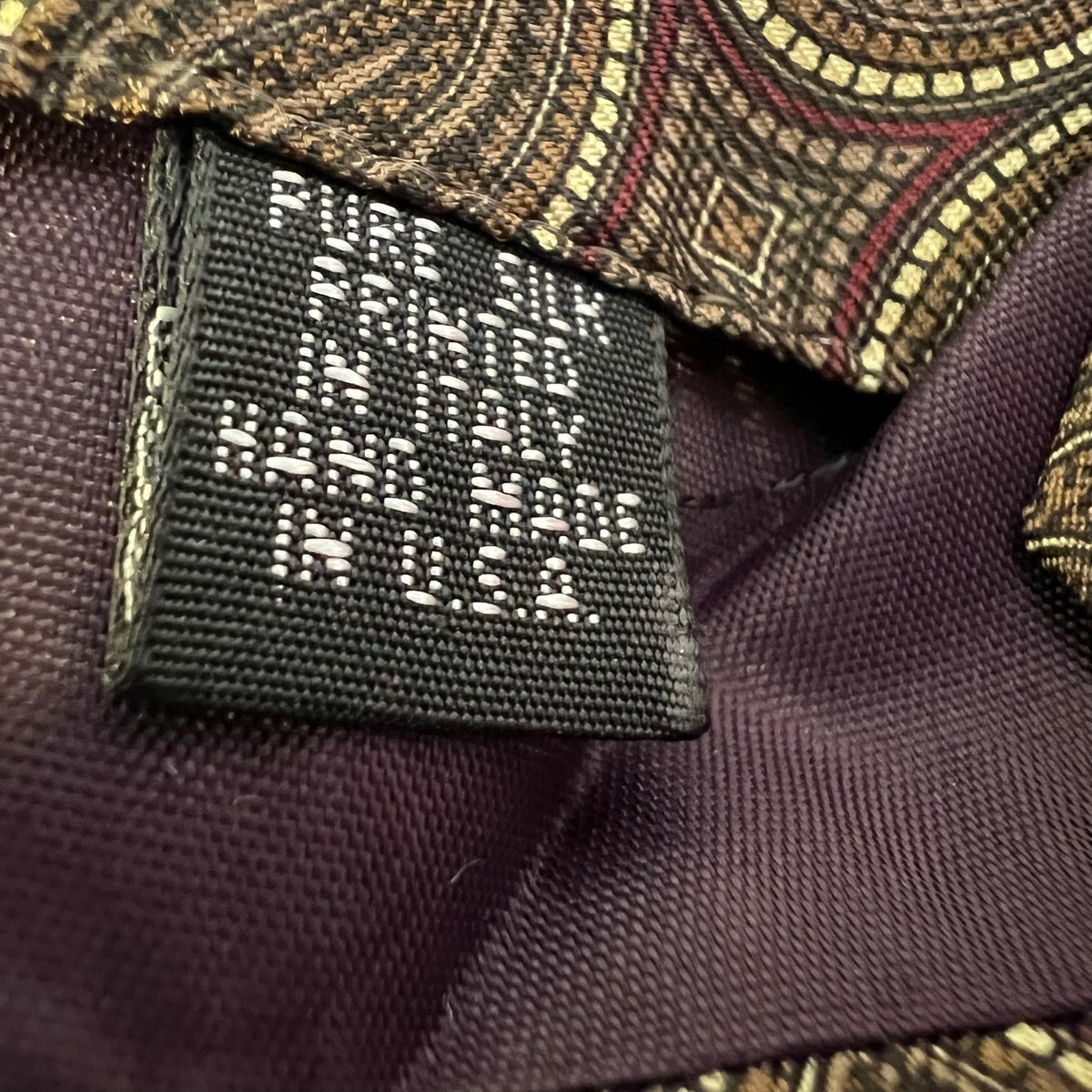 Close-up of a label on a suit with text 'Made in America' on a purple fabric background.