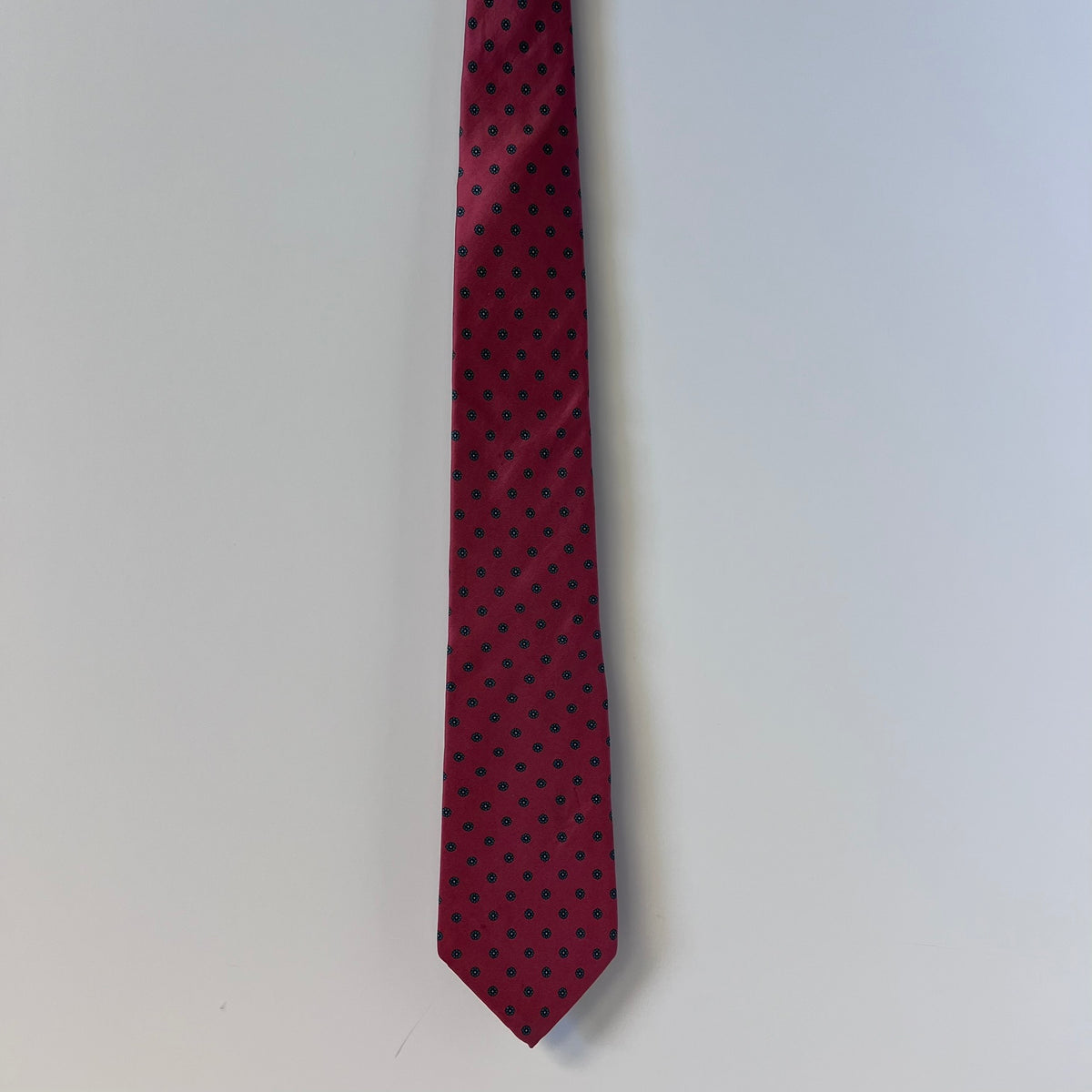 Red tie with black polka dots on a light gray background