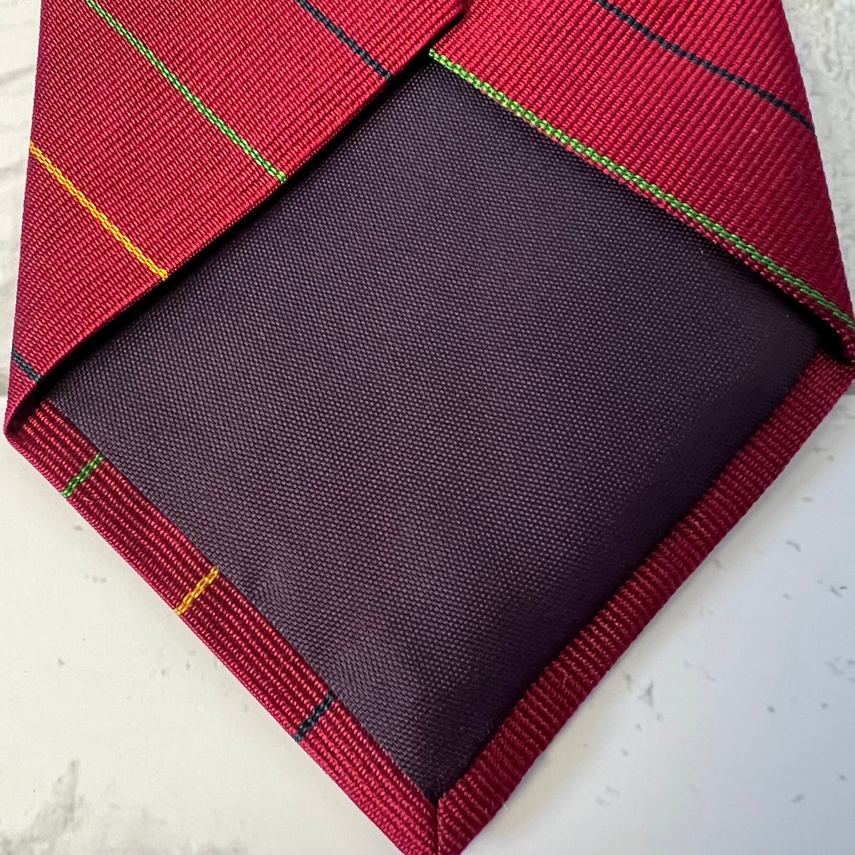 Red plaid tie with a dark pocket square on a light background
