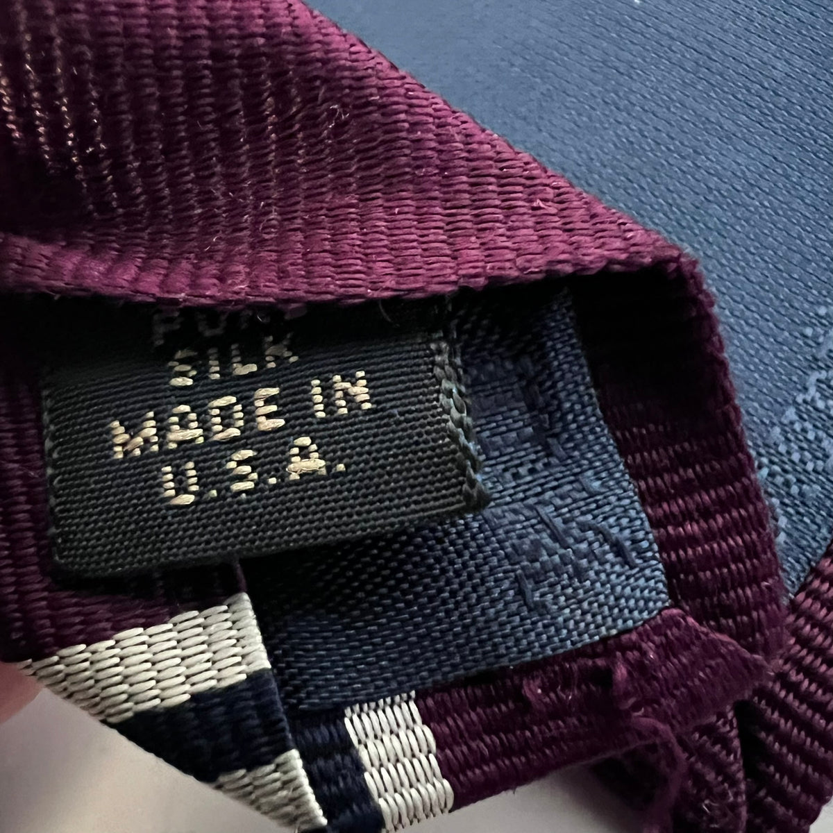 Close-up of a silk tie with 'Made in U.S.A.' label on a textured surface.