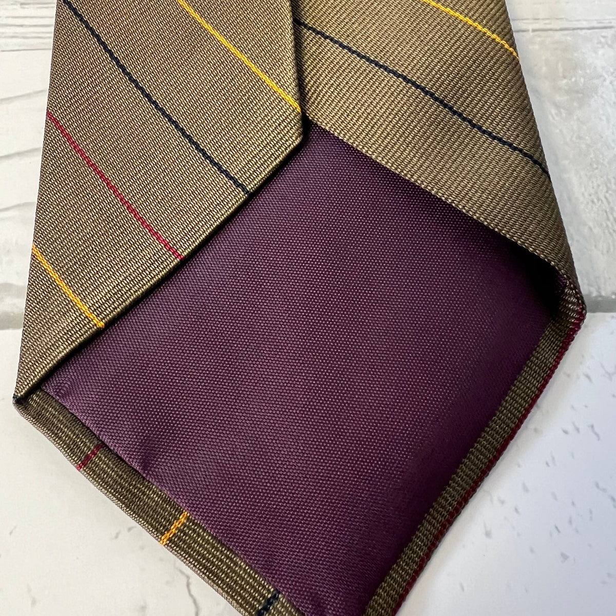 Woven fabric with plaid pattern and purple center on a white surface