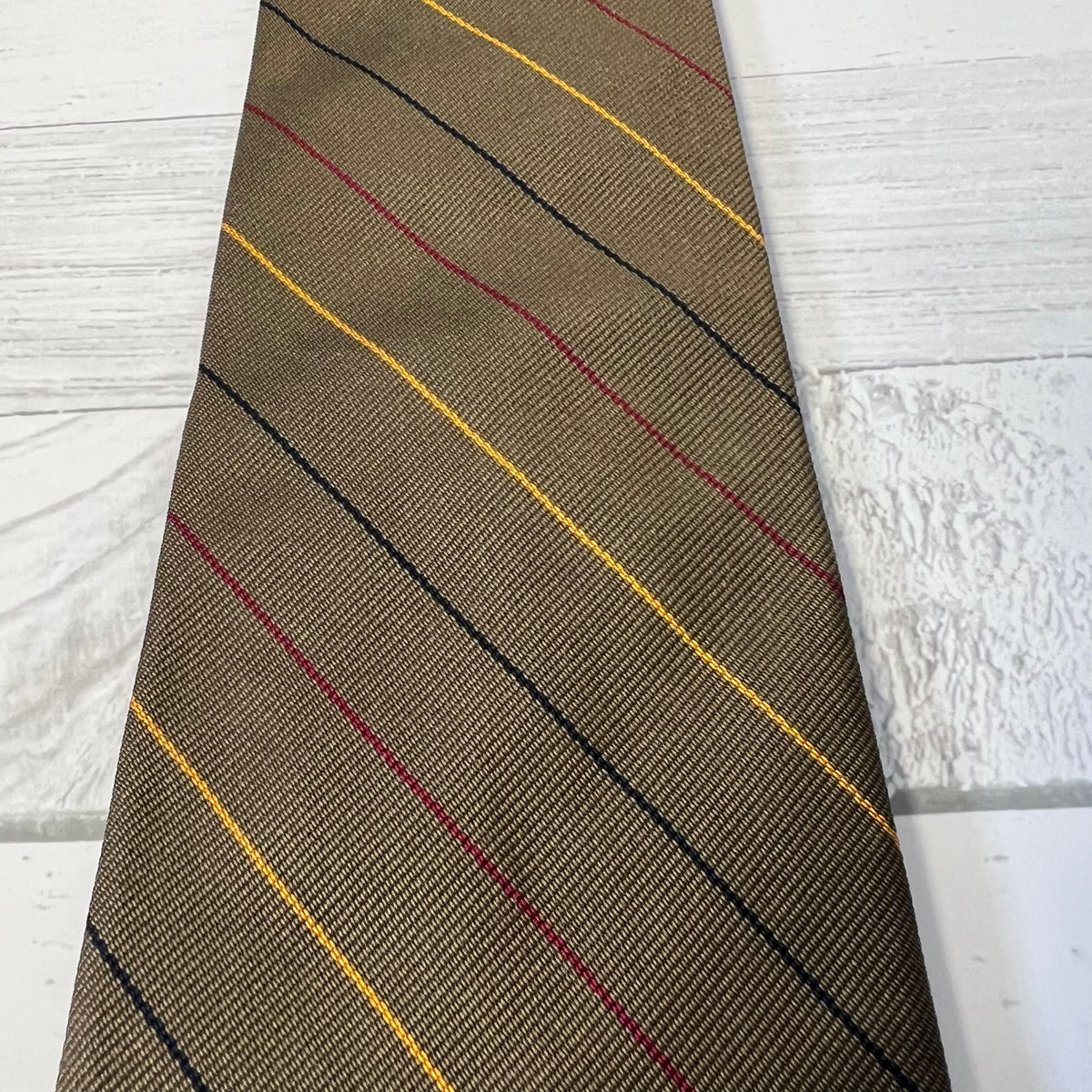 Brown tie with red and black diagonal stripes on a light wooden surface