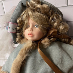 Close-up of a doll with curly hair wearing a gray outfit with fur trim.
