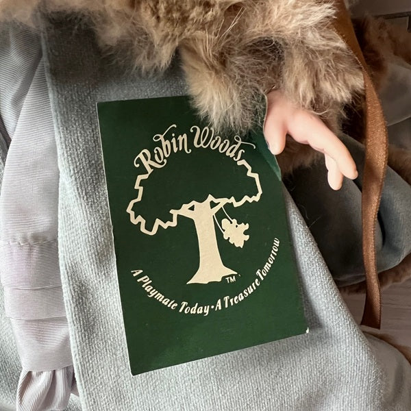 Green card with 'Robin Woods' logo tag attached to doll wearing a fur-lined coat.