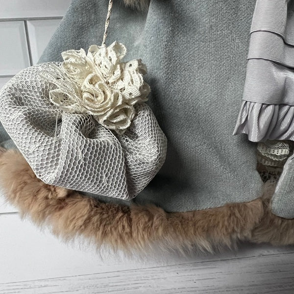 Gray textured bag with floral design and fur trim on a light wooden floor.