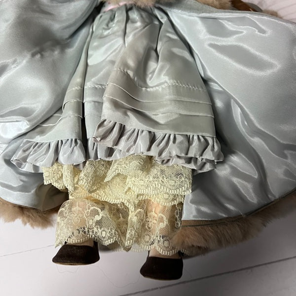 Close-up of a doll with a gray ruffled dress and lace hem on a white background