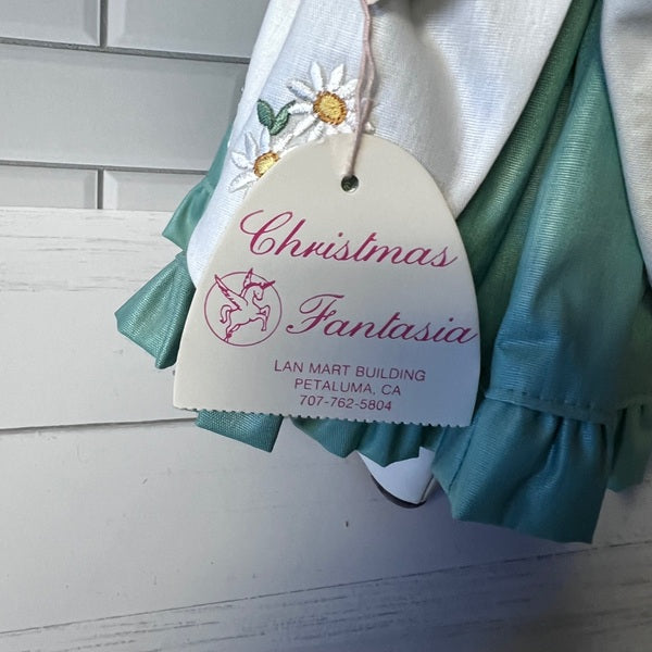 Teal and white dress with 'Christmas Fantasia' tag on a light wooden background
