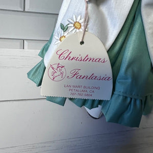 Teal and white dress with 'Christmas Fantasia' tag on a light wooden background