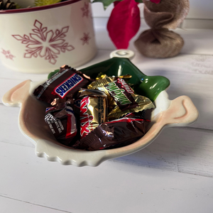Assorted chocolate bars in a decorative bowl on a white surface