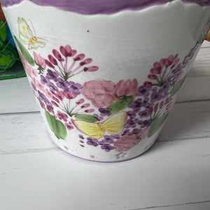Decorative pot with floral and butterfly design on a white surface