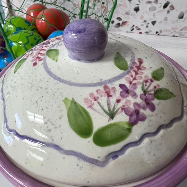 Ceramic lid with floral design and purple handle on a colorful background