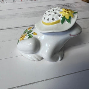 Ceramic frog-shaped container with a lid featuring floral designs on a wooden surface.