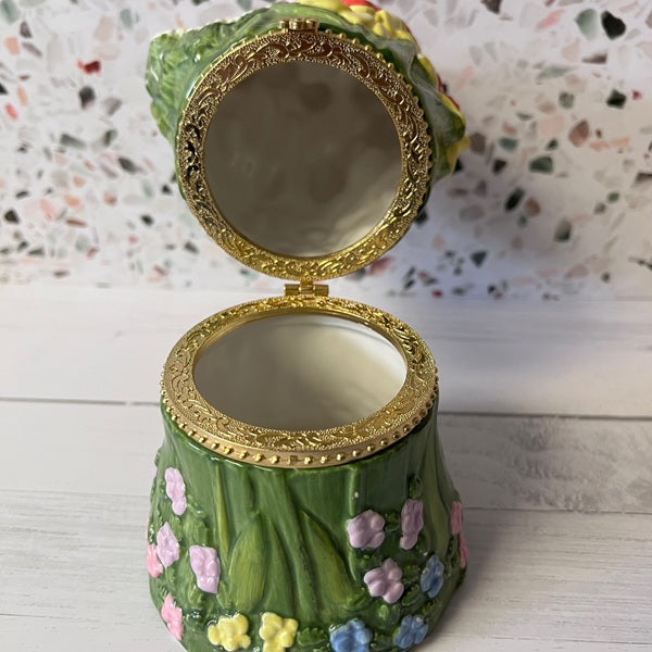 Decorative green container with gold lid on a white surface