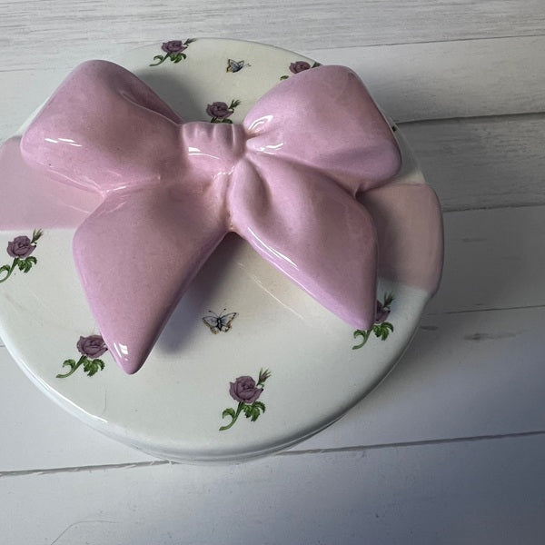 Pink bow-shaped object on a decorative plate with floral patterns