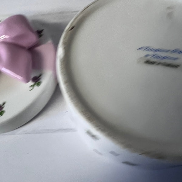 Close-up of a ceramic plate with floral design and another plate with text on a white surface.