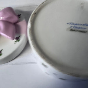Close-up of a ceramic plate with floral design and another plate with text on a white surface.