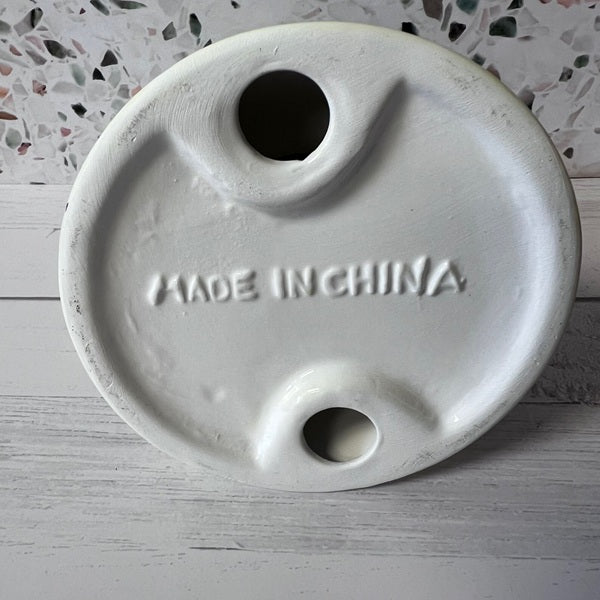 Round ceramic object with 'Made in China' engraving on a textured surface