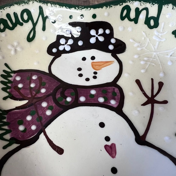 Decorative plate with a snowman design and text on a white background