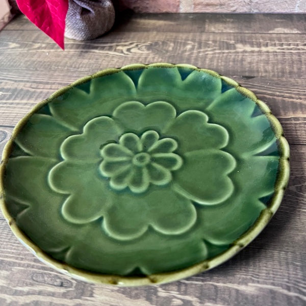 Green ceramic plate with floral design on a wooden surface