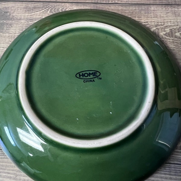 Green ceramic plate with 'HOME CHINA' branding on a wooden surface