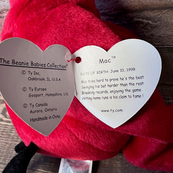 Heart-shaped tags on a red plush toy with branding and product details.