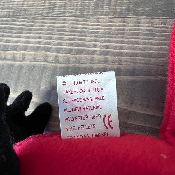 Product label on a red plush toy with a wooden surface background