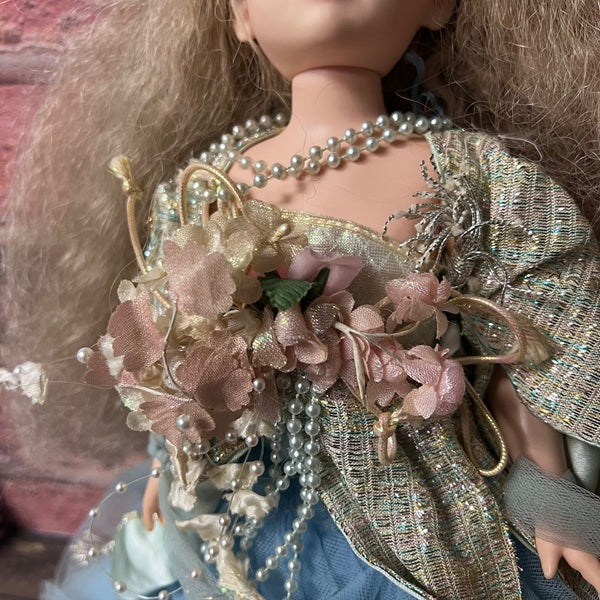Close-up of a doll with a bouquet of flowers and decorative clothing.