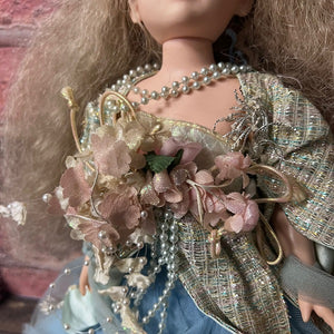 Close-up of a doll with a bouquet of flowers and decorative clothing.